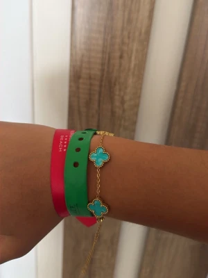 Guldarmband med turkosa pärlor-vancleef - Snyggt armband i guld med fyra fyrklöverformade turkosa pärlor. Kedjan är tunn och elegant, och pärlorna har en dekorativ guldkant runt sig. Perfekt accessoar för att lyfta din stil med en färgklick.