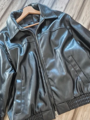Svart skinnjacka från Zara - Stilren svart skinnjacka från Zara med klassisk krage, dragkedja framtill och två snedställda fickor. Jackan har elastisk nederkant och raka ärmar för en modern look. Perfekt för dig som vill ha en tidlös och trendig jacka i garderoben.