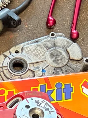Motordelar och verktyg - Säljer ett gäng motordelar inklusive en aluminiumkåpa och en röd cylinder från italkit. På bilden syns även två röda däckjärn och en del av en förpackning. Perfekt för dig som gillar att meka med mopeder eller små motorer.