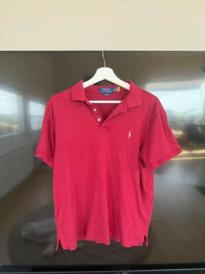 Röd pikétröja från Polo Ralph Lauren - Säljer nu min favorit Ralph Lauren piké eftersom jag växt ur den tyvärr. Den är gjord av skönt bomull och är köpt från Ralphlaurens hemsida för 1799. Storleken är L men skulle säga att den passar M. Tveka inte på att höra av dig!