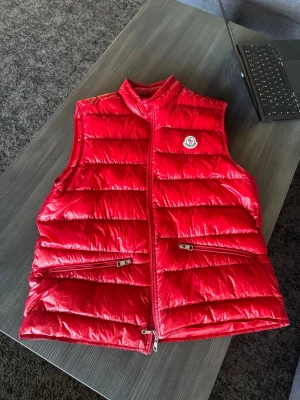 Moncler Gui Down Väst - Säljer min Mocler väst då den aldrig används. Köpte den på NK 2023 och sen dess använt den kanske 10 gånger annars har den fått hänga i gaderoben. Den är i mer eller mindre nyskick. Storlek "4".