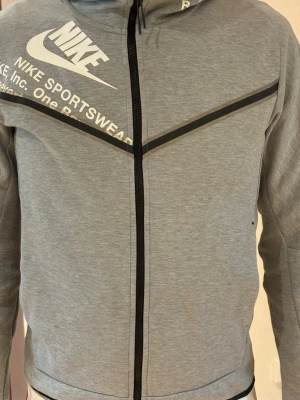 Grå Nike fleece tech stl S - Snygg grå hoodie från Nike med dragkedja framtill. Lite märke framtill på tröjan, knappt synligt, se bild3