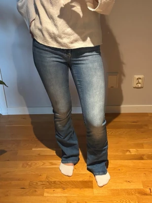 Blå bootcut jeans - Säljer ett par klassiska blå bootcut jeans med lätt utsvängda ben och snygg tvätt. Jeansen har normal hög midja. Tillverkade i stretchigt denimtyg.