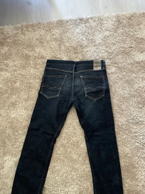 Replay jeans - Snygga mörkblå jeans med raka ben och klassiska fem fickor. Jeansen har kontrastsömmar och en diskret tvättad look. Passar perfekt till en avslappnad stil och är tillverkade i denim med en skön känsla.