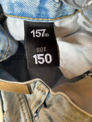 Ljusblå shorts  - Säljer ett par ljusblå jeansshorts från Lager 157 med klassisk femficksmodell och kontrastsömmar. Perfekta för en casual look och lätta att matcha med olika stilar. Den liten i storleken.