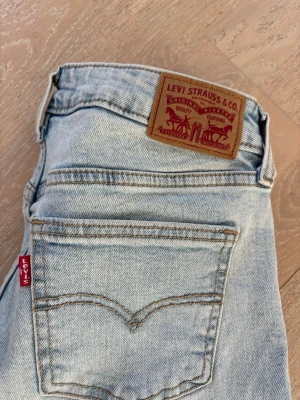 Ljusblå Levi's raka jeans - Säljer ett par klassiska ljusblå jeans från Levi's med raka ben och femficksmodell. Jeansen har den ikoniska röda Levi's-lappen på bakfickan och patch i läderimitation vid linningen. Tillverkade i slitstark denim, perfekta för en avslappnad look.