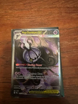 Mega Chandelure GX  Pokémonkort - Unikt Pokémonkort med Mega Chandelure GX-motiv. Kortet har holografisk yta och färger i lila, svart och silver. Text och effekter på engelska, HP 350 och attacker som Binding Flame och Phantom Maze. Perfekt för samlare eller Pokémonfans.