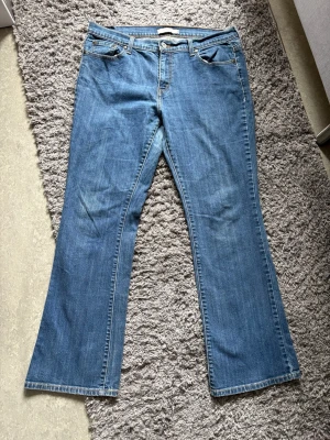 Blå bootcut jeans 515 från Levi's - Säljer ett par klassiska blå jeans från Levi's med bootcut passform. Jeansen har fem fickor, normal midja och den ikoniska röda Levi's-lappen på bakfickan. Tillverkade i slitstark denim med snygga kontrastsömmar.