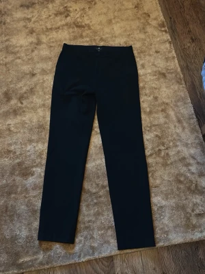 Svarta HM kostymbyxor - Snygga svarta kostymbyxor med rak passform och klassisk midja. Byxorna har en stilren look utan synliga detaljer och är perfekta för en clean outfit. Materialet ser ut att vara en mjuk och följsam textil som ger en dressad känsla. Nypris 599kr passar 173-180. Använd 5 gånger.