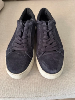 Vagabond mockasneakers med vit sula - Vagabondsneakers i mocka med matchande mörkblå skosnören och vit, tjock gummisula. Klassisk låg modell som passar till det mesta.