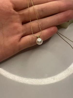 Guldhalsband med en pärla - Ett elegant halsband med guldfärgad kedja och en rund vit pärla som hänge. Har bara använt halsbandet två gånger och det ska vara rostfritt🫶🏻