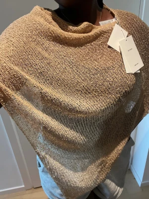 Beige stickad sjal från Jaded london - Säljer en snygg beige sjal i meshstickat material. Helt oanvänd från Jaded London, nypris: 445kr.
