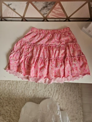 Rosa blommig volangkjol - Supersöt rosa kjol. Shorts under perfekt ju! Helt nya kanske har haft den 1-2 gånger men super bra skick verkligen. Hör av er vid intresse. Kostar 60 och helt ny typ 1-2 gånger använd och igentligen kostar den 200💕