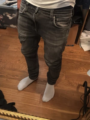 Nudie jeans slim fit - Säljer ett par grå slim fit jeans med slitningar och snygga detaljer på fickorna. ,jeansen har en tvättad look med markerade sömmar som får dem att utstå som Archive, det här är mina favorit jeans men tyvär har jag växt ut dem bästa köpet jag gjort.