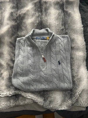 Grå kabelstickad tröja Polo Ralph Lauren - Säljer min Ralph Gråa  Lauren Half-Zip stickade tröja.  I nyskick – endast använd ett fåtal gånger och mycket väl omhändertagen. Stilren, bekväm och passar perfekt till både vardag och finare tillfällen. Storleken  är L men Ralph lauren är liten i storleken speciellt på halfzips därför rekommenderas att köpa den ifall du normalt vis har M för bättre passform ❗️ ✅ Äkta Ralph Lauren ✅ Mycket fint skick ✅ Inga fläckar eller skador  Skicka ett meddelande vid intresse!