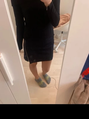 Svart kortkjol med slits - Säljer en svart kortkjol med en liten slits på sidan. Kjolen har en enkel och stilren design som passar till många olika outfits. Materialet ser ut att vara mjukt och följsamt, och modellen är normal i passformen.