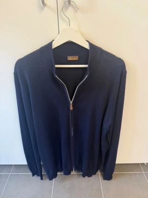 Mörkblå ziptröja från Stenströms, stl XL - Mörkblå stickad ziptröja från Stenströms med hel dragkedja framtill och ribbade muddar. Klassisk och stilren modell som passar perfekt till lager-på-lager. Tillverkad i mjukt material för en bekväm känsla.