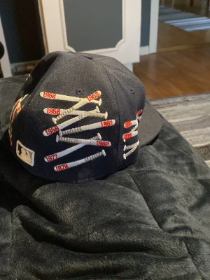New Era keps - Snygg blå New Era 59FIFTY keps med New York Yankees-logga framtill, 55.8cm. På sidan finns broderade basebollträn med årtal i rött och vitt. 