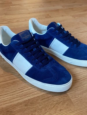 Valentino Flycrew - Valentino Flycrew i blå mocka med vita detaljer och vit sula. Skorna har blå skosnören och en klassisk låg profil. Märkeslogga på plösen och insidan är vit. Perfekta för dig som vill ha en stilren och trendig look. Skriv vid intresse, försöker alltid frakta samma dag. 