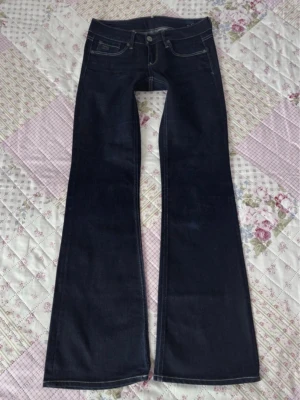 Mörkblå bootcut jeans  - Snygga mörkblå bootcut jeans med klassisk femficksmodell och kontrastsömmar. Jeansen har utsvängda ben och låg midja. Kan diskutera pris