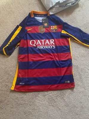 Barcelona långärmad matchtröja - Säljer en långärmad FC Barcelona matchtröja från Nike med breda röda och blå ränder, gula detaljer och klubbmärke på bröstet. 