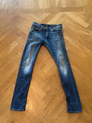 Blå replay  slim fit jeans med slitningar - Snygga blå slim fit jeans med slitna detaljer på framsidan och baksidan. Klassisk femficksmodell med låg midja och dragkedja. Jeansen har en tvättad look och är gjorda i denim, perfekt för en avslappnad stil. Dem är ifrån replay och nypris är runt 1500kr, dem är u väldigt bra skick och är inte använda mycket, mitt pris är 499kr. Skriv dm för frågor 