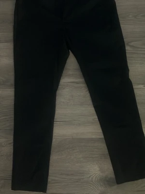 Svarta raka kostymbyxor - Snygga svarta kostymbyxor med rak passform och klassisk midja. Byxorna har en stilren look och är perfekta för dig som gillar en clean och enkel stil. Materialet ser ut att vara vävt tyg som ger en dressad känsla.  54 midjan 32 längd 