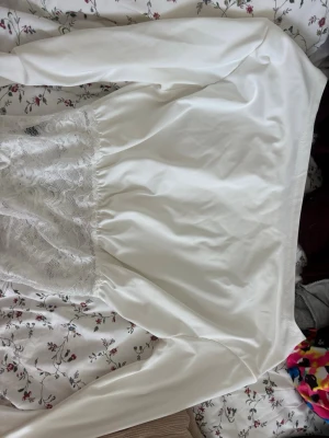 Vitt bluse med spetsdetaljer - Säljer en elegant vitt  blouse med långa ärmar och vackra spetsdetaljer nedtill. Materialet känns mjukt och följsamt. Spetsen ger en romantisk touch och blusen har en klassisk, tidlös look.