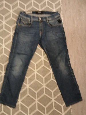 Blå jeans från Replay - Säljer ett par klassiska blå jeans från Replay med fem fickor och knappgylf. Jeansen har en lätt tvättad look och raka ben. Perfekta till en avslappnad stil och passar till det mesta i garderoben.