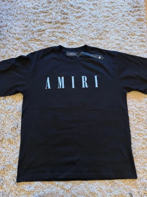 Svart t-shirt  - Svart t-shirt från A med stort vitt logotryck på bröstet. Klassisk rund halsringning och korta ärmar. Perfekt för en stilren och trendig look.