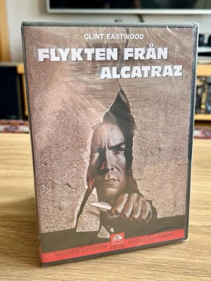 Flykten från Alcatraz – DVD – ny och inplastad - Säljer Flykten från Alcatraz (Escape from Alcatraz) med Clint Eastwood på DVD.  En riktig fängelseklassiker från 1979, regisserad av Don Siegel och baserad på den berömda rymningen från Alcatraz.  Detta exemplar är fortfarande fabriksinplastat och oöppnat och kommer från Paramounts Widescreen Collection – ett extra fint exemplar för filmsamlaren eller Clint Eastwood-fantasten. 🎬  Skick: Ny / oöppnad / inplastad Format: DVD Utgåva: Widescreen Collection  Skickas väl emballerad.