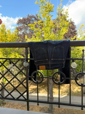 Mörkblå Nudie jeans - Säljer ett par mörkblå jeans med klassiska bakfickor och kontrastsömmar. Jeansen har en läderpatch bak i midjan och är tillverkade i ett kraftigt denimtyg. Perfekta för dig som gillar en stilren och enkel look. Storlek W27 L32