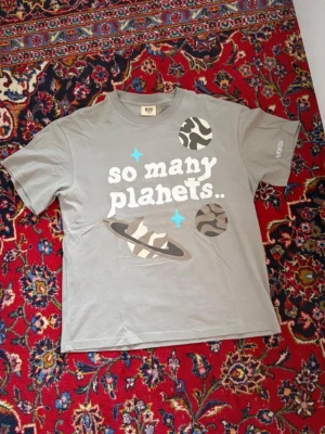 Grå t-shirt Broken Planet planets - Säljer en grå t-shirt från Broken Planet med tryck av planeter och texten 'so many planets..' på framsidan. T-shirten har korta ärmar och är gjord i mjuk bomull. Perfekt för dig som gillar streetwear och coola prints.