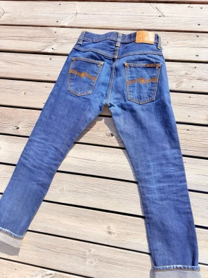 Selvage Nudie Jeans Grim trim - Säljer ett par Selvedge Jeans från Nudie gjort av 100% bomull i italien. Jeansen är knappast använda vilket gör att nästa ägare kommer att kunna få feta fades efter användning. Storlek W29 L30 Mått lårvidd 24cm / Innerbenlängd 72cm / Midja 36cm. Priset ej hugget i sten, kom gärna med frågor och prisförslag! 😁