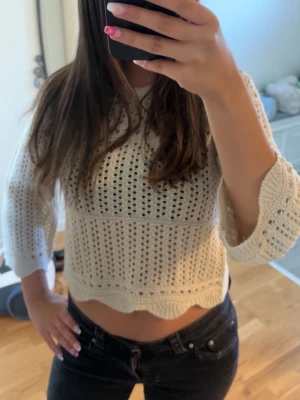 Beige virkad cropped stickad tröja - Säljer en beige stickad tröja i virkad stil med hålmönster och 3/4-ärmar. Tröjan är croppad med vågig kant nertill och har en avslappnad passform. Perfekt till jeans eller kjol för en trendig look!💞 