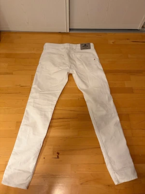 Vita slim fit jeans från Replay, W31 L32 - Säljer ett par vita slim fit jeans från Replay med klassisk femficksmodell och silverfärgade nitar. Jeansen har normal midja och är tillverkade i ett mjukt bomullsmaterial med lite stretch för extra komfort. Perfekta för dig som vill ha en clean och fräsch look. Priset kan diskuteras.