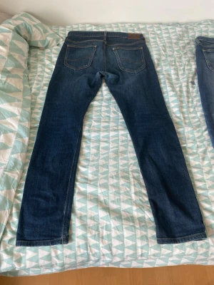 Lee jeans slim - Snygga mörkblå jeans med raka ben och klassisk femficksdesign. Jeansen har kontrastsömmar och en läderpatch bak i midjan. Perfekta till vardagslooken och passar till det mesta. Materialet är troligtvis bomull med lite stretch.