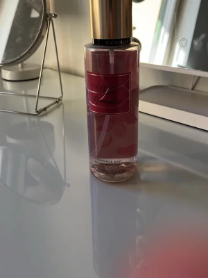 Victoria's Secret Romantic mist - En snygg parfymmist från Victoria's Secret i doften Romantic. Flaskan är genomskinlig med rosa vätska och har en guldig kork. Etiketten är rosa med guldiga detaljer. Perfekt för dig som gillar blommiga och fräscha dofter.