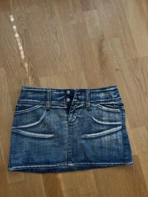 Blå jeanskjol med dubbla knappar - Säljer en kort blå jeanskjol med dubbla knappar framtill. Storlek S 