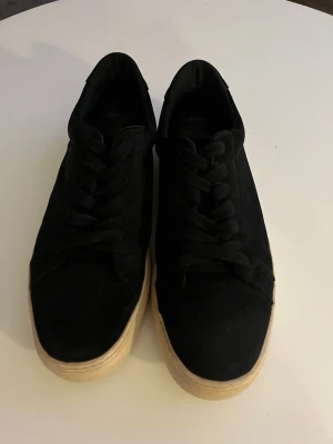 Svarta vagabond sneakers - Stilrena svarta sneakers i mockaliknande material med beige, tjock sula. Klassisk låg modell med svarta skosnören och enkel design som passar till det mesta. Perfekta för dig som gillar en clean och tidlös look.