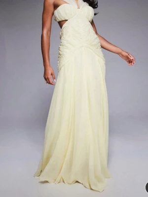 Ljusgul långklänning  - Helt ny och aldrig använd ljusgul maxiklänning från ASOS LUXE. Lyxig modell i organza och chiffong med halterneck, vacker rynkad design och svepande fall. Priset går att diskuteras