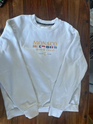 Vit sweatshirt med Monaco-brodyr - Vit sweatshirt med Monaco brodyr. Väldigt bra skick då den inte riktigt passa min stil och är lite för stor för mig. Riktigt skön inuti och perfekt nu till hösten och vintern.