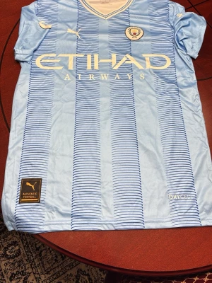 Manchester City matchtröja Puma - Säljer en ljusblå Manchester City matchtröja från Puma med HAALAND och nummer 9 på ryggen. Tröjan har vita detaljer, klubbmärke på bröstet och sponsorloggor. Tillverkad i funktionsmaterial (DryCell) perfekt för fotbollsträning eller match.