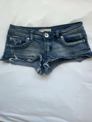 Blå jeansshorts med fransar - Säljer ett par blå vintage lågmidjade jeansshorts. Storlek 34/xs. Skriv angående frågor eller prisförslag. 💕