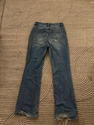 Blå bootcut jeans med rå kant - Ett par klassiska blå bootcut jeans, lite slitna nertill men fortfarande i ett väldigt bra och fint skick, det är storlek 38 men funkar för folk som har 36 också 