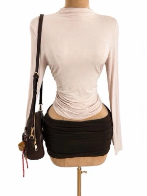 Ljusbeige långärmad polotopp - Trendig ljusbeige polotopp med lång ärm och figurnära passform. Toppen har en slät yta och lätt glansigt material som ger en stilren look. Perfekt att styla med kjol eller jeans för en snygg outfit.