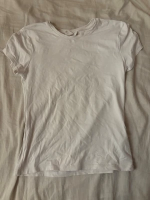 Vit basic t-shirt  - En enkel vit t-shirt i mjuk bomull med rund hals och korta ärmar. Perfekt att matcha med jeans eller shorts för en clean och avslappnad stil. Klassisk passform och tidlös design. Storlek M men kan sitta som S.