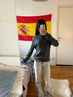 Mörkgrå kabelstickad tröja - Mysig mörkgrå kabelstickad tröja med rund halsringning och långa ärmar. Tröjan har ribbade muddar vid ärmslut och nederkant, vilket ger en snygg och klassisk look. Perfekt att matcha med jeans eller kjol för en avslappnad stil.
