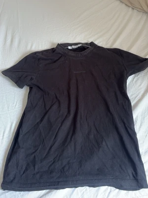 Svart Calvin Klein Jeans t-shirt - Svart t-shirt från Calvin Klein Jeans med diskret logga på bröstet och tryck i halsringningen. Klassisk passform och rund hals. Perfekt till jeans eller shorts för en clean och enkel look.