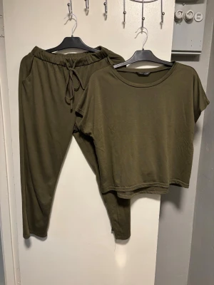 Olivgrönt loungewear-set från SHEIN - Mysigt loungewear-set i olivgrönt från SHEIN. Setet består av en kortärmad, lös t-shirt med rund hals och ett par byxor med resårmidja och dragsko samt fickor. Perfekt för chill dagar hemma. Materialet känns mjukt och stretchigt.